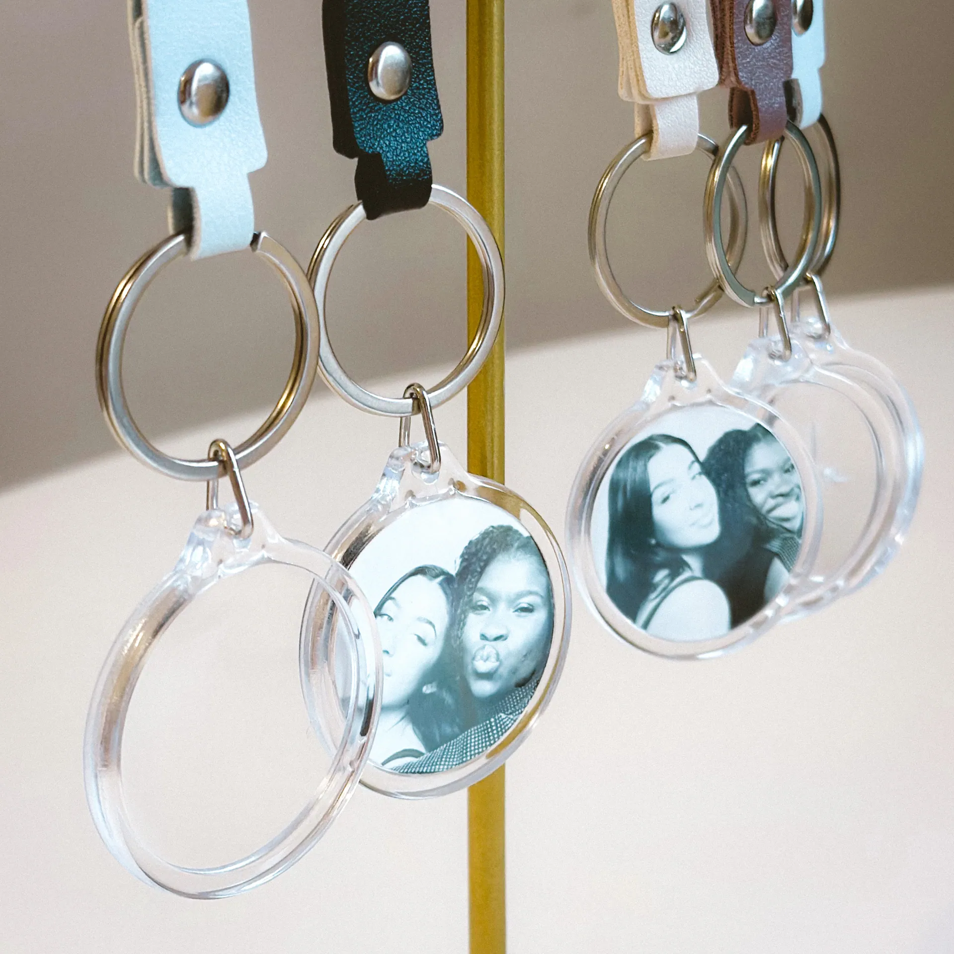 Clear acrylic photo keychains displayed on a gold stand