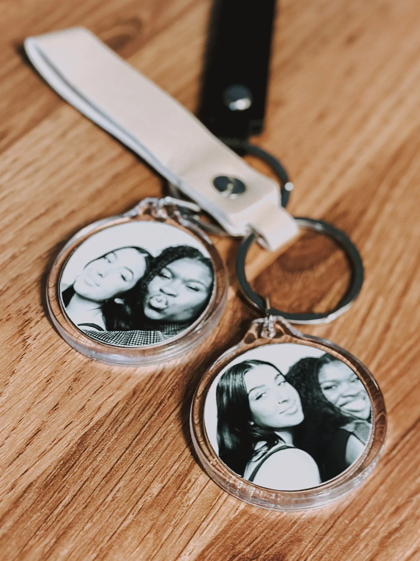 Custom round photo keychains with guest portraits and ribbon bands on a wooden table