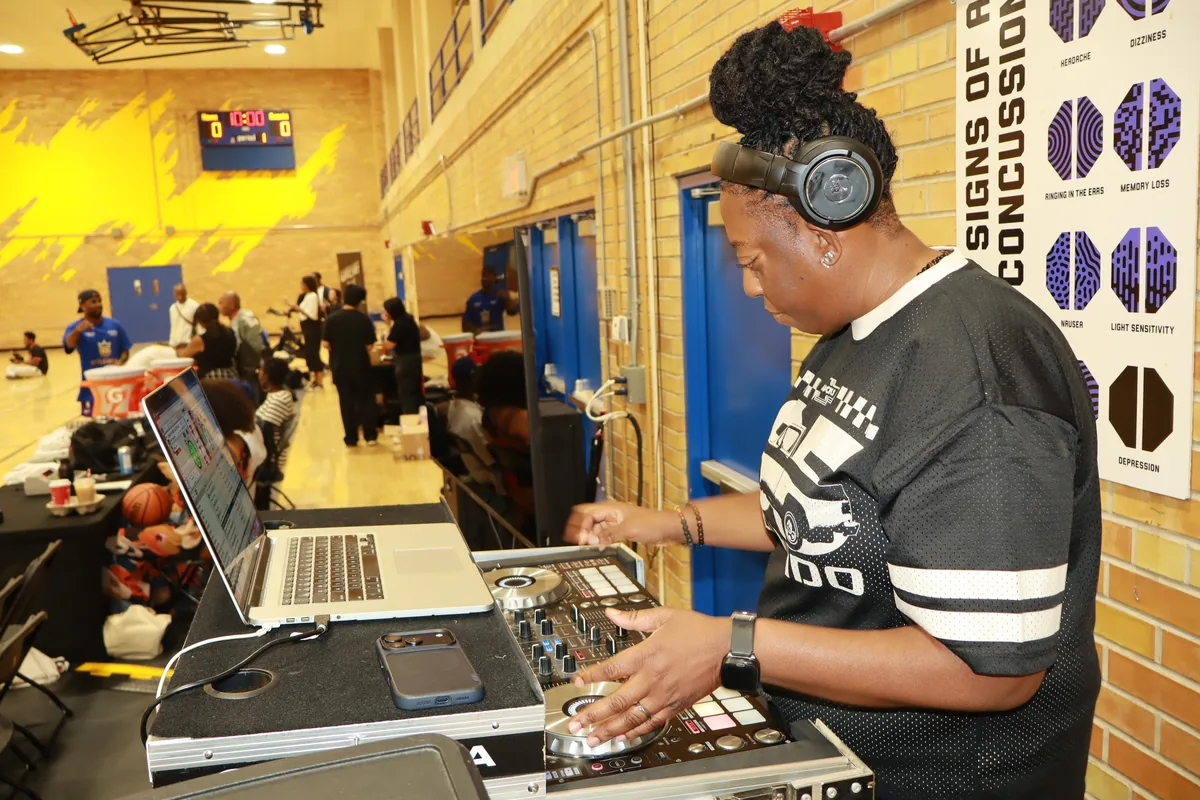 DJ JJ Rock wearing headphones and operating a DJ controller in a gym