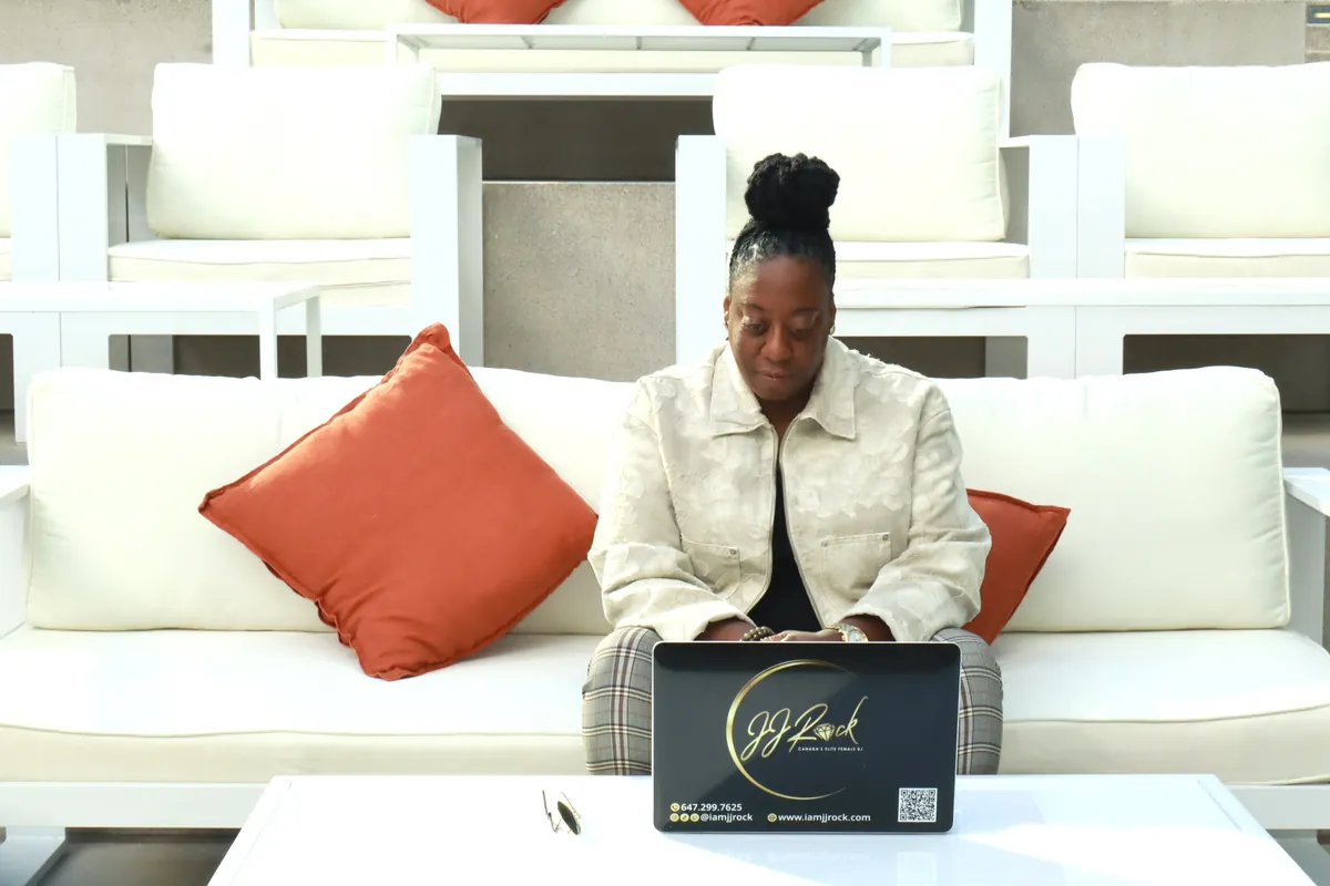 DJ JJ Rock curating music on her branded laptop at the Black Excellence Brunch