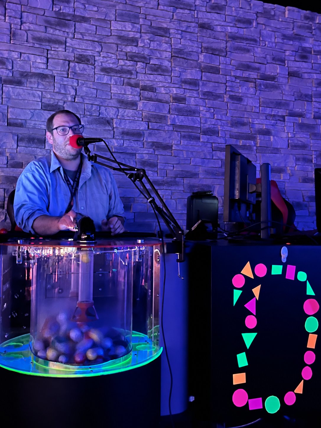Bingo caller at the microphone beside the illuminated bingo machine