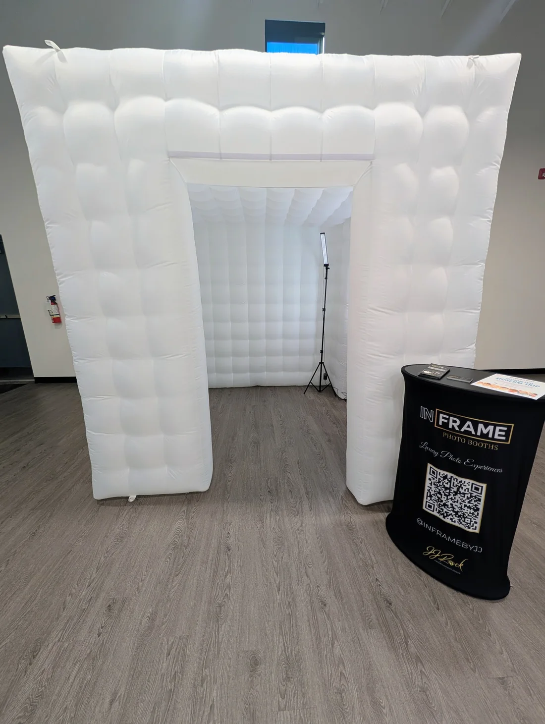White walk-in inflatable enclosure set up indoors with an In Frame photo booth station