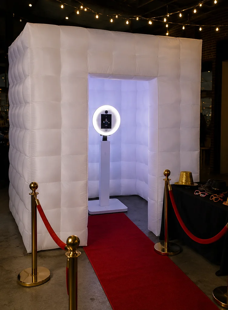 White inflatable enclosure with a photo booth inside, red carpet and gold stanchions at Taste of the Caribbean