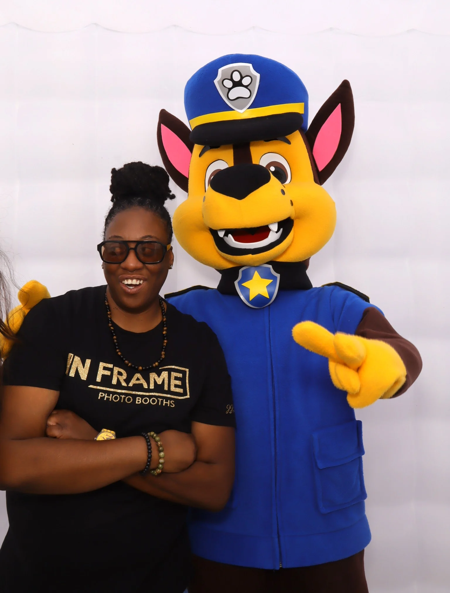 An In Frame team member posing with a costumed mascot at a photo booth