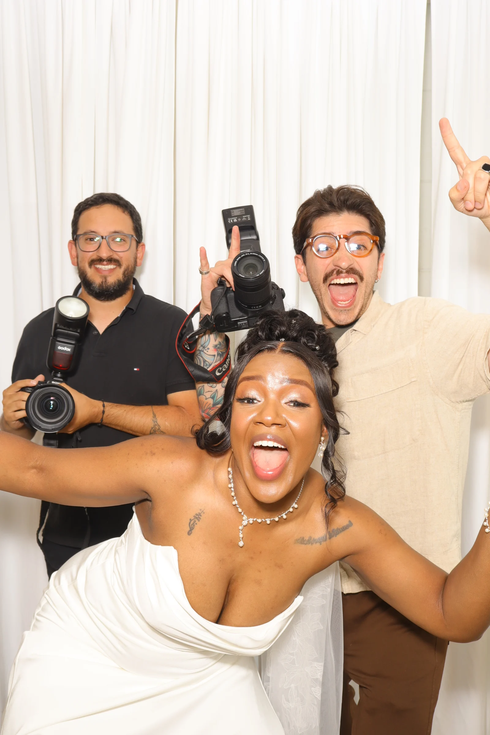 Bride laughing with two guests in a wedding photo booth