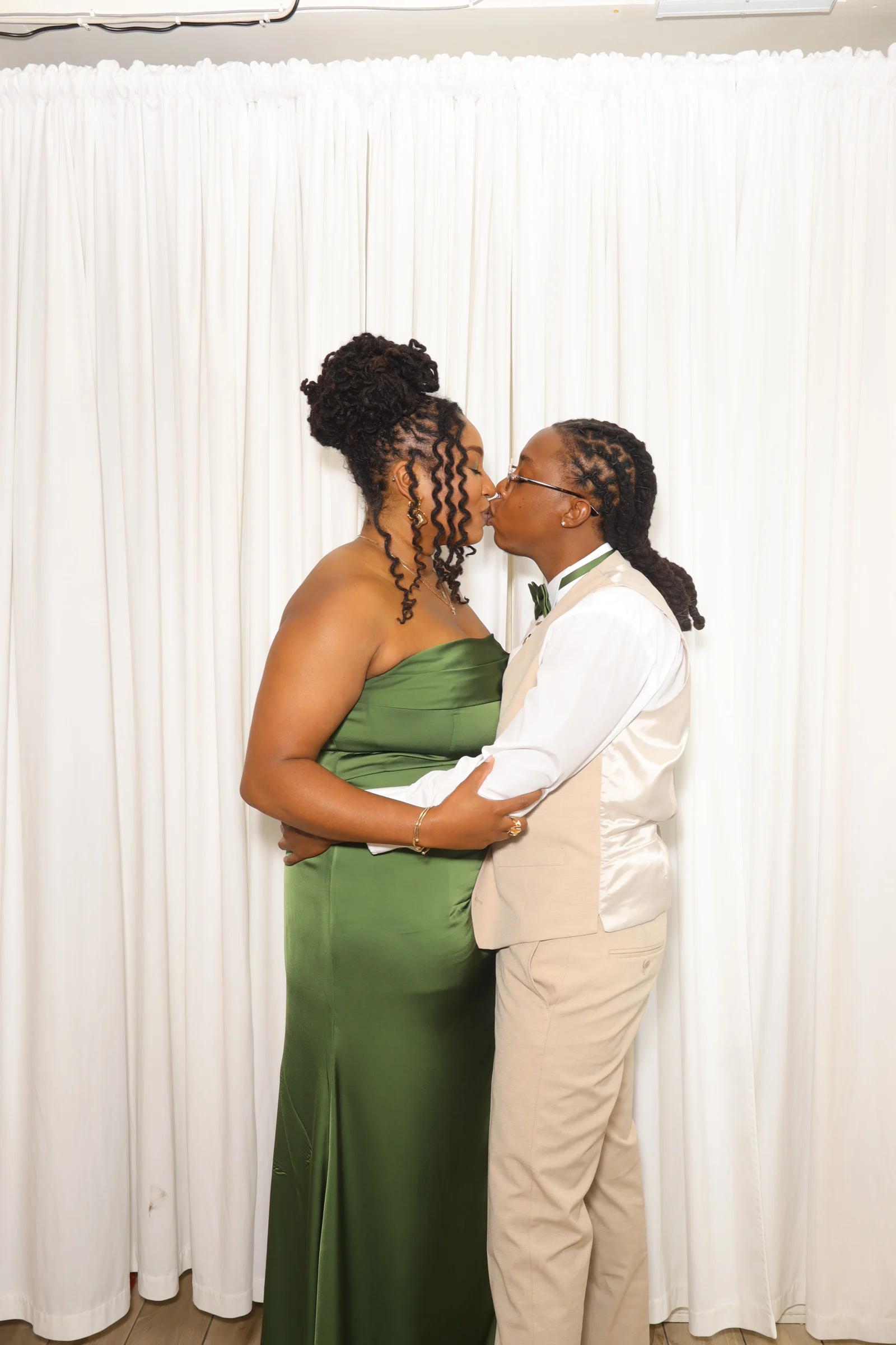 Two wedding guests sharing a kiss at the photo booth