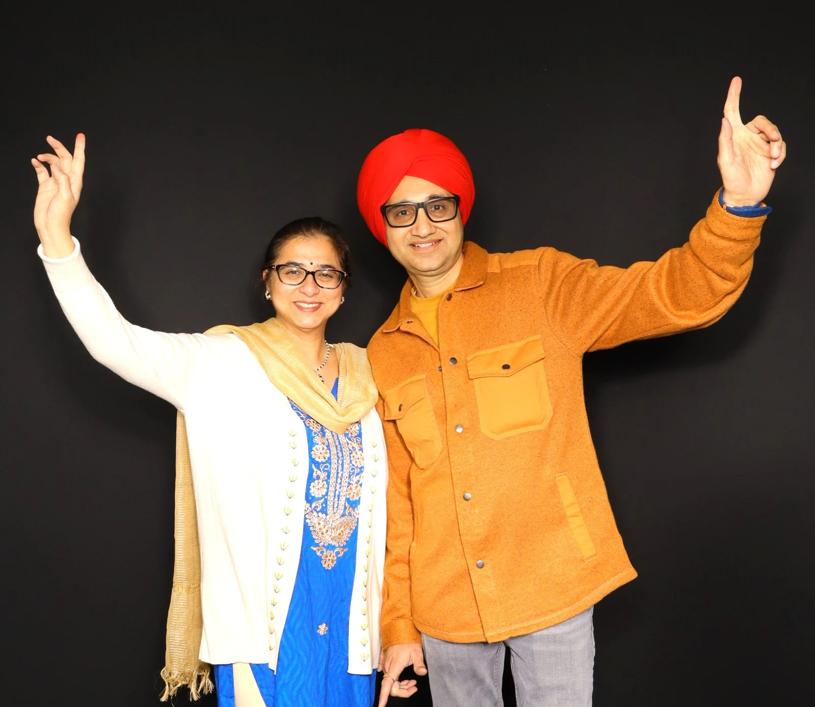 Two guests smiling with their arms raised against a dark backdrop